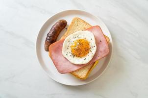 pain maison, fromage grillé, jambon garni et œuf au plat avec saucisse de porc pour le petit-déjeuner photo