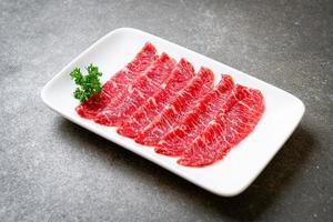 boeuf frais cru tranché avec texture marbrée servi pour sukiyaki et shabu ou yakiniku photo