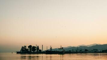 Matin digue de le Port avec bois flotté contre le Contexte de le collines derrière photo