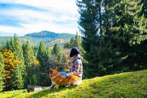 jeune femme voyageur avec chien corgi dans les montagnes photo