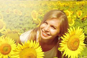 Souriante jeune femme en champ de tournesols, temps d'agriculture en campagne photo
