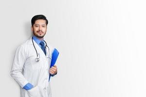 Docteur en blouse de laboratoire tenant un dossier patient ou des notes médicales regardant la caméra, isolé sur fond blanc photo