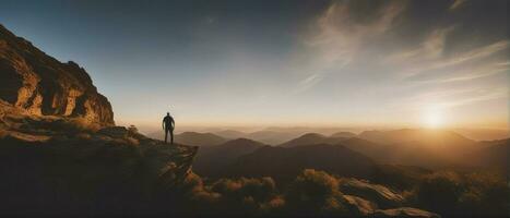 Jeune homme permanent sur Haut de falaise dans été montagnes à le coucher du soleil et profiter vue de nature, génératif ai photo