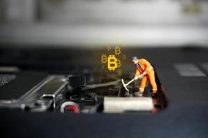 figure de travailleur technicien debout sur un ordinateur portable. concept de crypto-monnaie bitcoin.