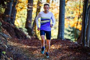 coureur d'athlète professionnel s'entraîne parmi les feuilles des bois photo