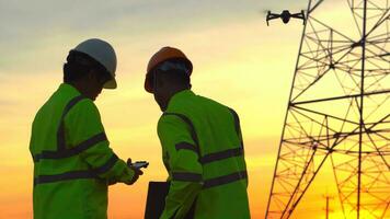 silhouette de ingénieur équipes à la recherche discuter planifier. deux ingénieur permanent sur champ avec électricité tours à le coucher du soleil. photo