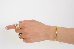 femme main portant d'or serpent chaîne bracelet et interverrouillé d'or et argent anneaux ensemble contre une blanc Contexte. magnifique la Saint-Valentin cadeau. photo