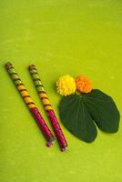 festival indien dussehra et navratri, montrant des fleurs de bauhinia racemosa et de souci avec des bâtons de dandiya sur fond vert photo