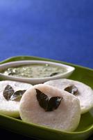 idli avec chutney de noix de coco sur fond bleu, plat indien plat préféré de l'Inde du Sud rava idli ou semoule oisivement ou rava oisivement, servi avec du sambar et du chutney de noix de coco verte.