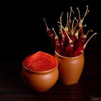 poudre fraîche avec du piment rouge dans des pots en argile, piments séchés sur fond sombre photo
