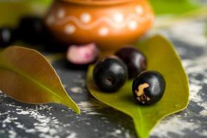 prune jambolan ou fruit jambul ou jamun, prune de java syzygium cumini avec feuille sur fond texturé en pierre. photo