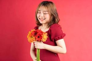 Jeune fille tenant un bouquet de gerberas avec une expression joyeuse sur fond photo
