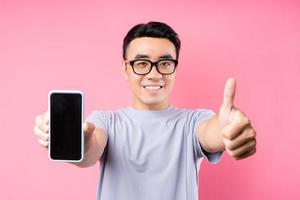 portrait d'un homme asiatique utilisant un smartphone sur fond rose photo