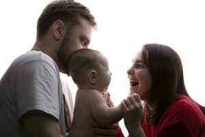 proche en haut portrait de Jeune Parents et bébé. père et mère étreinte et jouer avec une magnifique peu fils. le concept de aimer, content paternité et maternité. photo