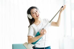 femme asiatique écoutant de la musique et dansant avec un aspirateur photo