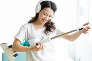 femme asiatique écoutant de la musique et dansant avec un aspirateur photo