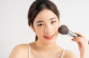 jeune fille asiatique tenant un pinceau de maquillage pour elle-même photo