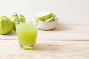 verre de jus de goyave frais avec des fruits de goyave frais sur table en bois photo