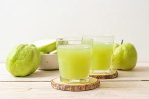 verre de jus de goyave frais avec des fruits de goyave frais sur table en bois photo