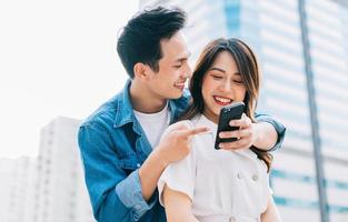 jeune couple asiatique utilisant un smartphone ensemble dans la rue photo