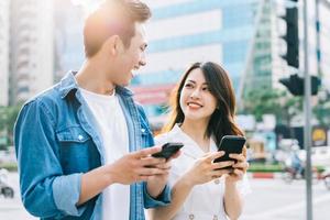 jeune couple asiatique utilisant un smartphone ensemble dans la rue photo