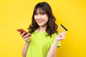 jeune fille tenant un téléphone et une carte de crédit avec une expression joyeuse sur fond photo