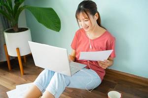 femme asiatique assise sur le sol pendant qu'elle travaille à domicile photo