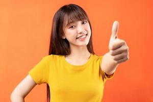 image de jeune fille asiatique portant un t-shirt jaune sur fond orange photo