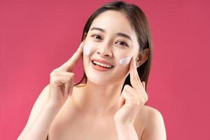 femme asiatique joyeuse avec une belle peau à l'aide de lotion photo