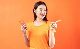 image de jeune femme asiatique tenant un smartphone sur fond orange