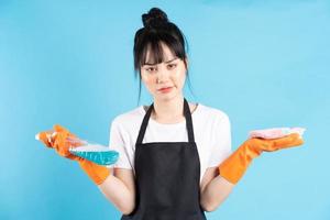 femme au foyer asiatique porte des gants orange et tient un jet d'eau dans sa main photo