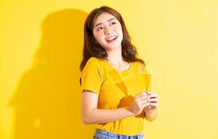 jeune femme asiatique buvant du vin et posant sur fond jaune