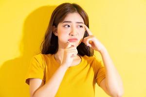 Jeune femme asiatique mangeant une sucette sur fond jaune photo