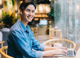homme asiatique assis à l'aide d'un ordinateur portable dans un café photo