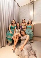 une groupe de asiatique femmes dans glamour et luxueux vêtements sont séance sur le canapé avec leur copains après faire la fête photo
