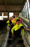 une groupe de asiatique Hommes dans citron vert vestes sont permanent avec leur copains sur le escalier mécanique photo