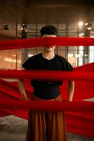 un asiatique homme permanent fièrement parmi le rouge tissu cette se balance dans un vieux bâtiment photo