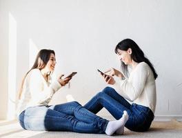 deux belles amies envoyant des messages avec des téléphones portables photo