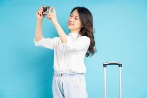 belle femme asiatique prenant une photo avec une valise à côté d'elle