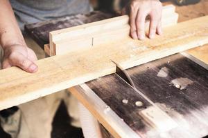 les opérateurs de menuiserie utilisent des machines de découpe de planches pour assembler et construire des tables en bois pour les clients. photo