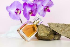 une parfum bouteille des stands sur une pierre contre une Contexte de magnifique orchidées. élégant apparence, mise en page, personnalité. bannière, une endroit pour le texte. photo