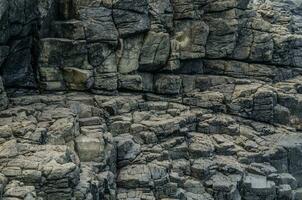 gris côtier Roche mur, sédimentaire rochers formé par le accumulation ou déposition de minéral ou biologique particules à la terre surface modèle. photo