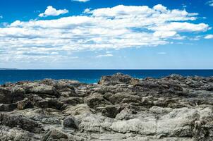 Naturel côtier Roche surface avec nuageux ciel et bleu océan l'eau dans Kiama, un de le principale touristique attractions dans Nouveau Sud Pays de Galles, Australie. photo