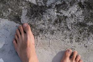 le Jeune homme pieds flottait sur une différent ciment sol. pieds sont ne pas fort, avoir besoin à être prudent photo