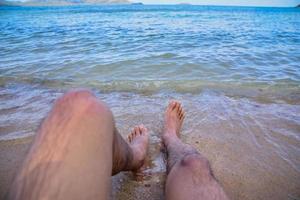 l'homme est sur la plage et les pieds dans la mer photo