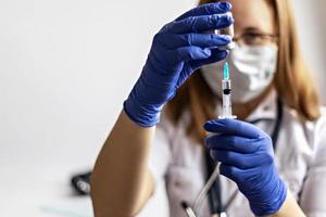 une femme médecin portant un masque médical aspire le vaccin contre le coronavirus dans une seringue à la clinique.le concept de vaccination, d'immunisation, de prévention contre le covid-19. photo