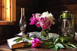 nature morte d'objets vintage et un bouquet de pivoines sur une table près de la fenêtre dans une ancienne maison de village. photo