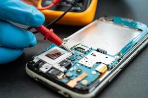 technicien réparant l'intérieur du téléphone portable en fer à souder. circuit intégré. le concept de données, de matériel, de technologie. photo