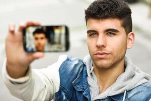 jeune homme selfie en arrière-plan urbain avec un smartphone