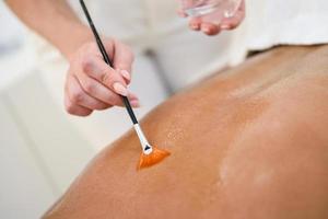 femme recevant un massage du dos avec une brosse à huile photo